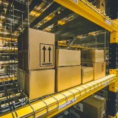 Pudełka z symbolami strzałek w górę czekają na sprawną rękę logistyka w magazynie.
