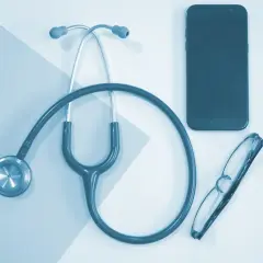 Stetoskop, okulary i telefon leżą obok siebie. To może być pomocne przy pytaniu, jak obliczyć dochód do składki zdrowotnej.