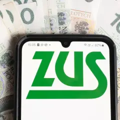 Telefon z logo ZUS na tle banknotów 100 zł. To symbol współpracy i finansów.