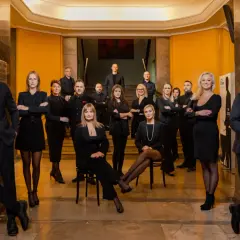 Grupa profesjonalistów w eleganckich czarnych strojach pozuje w holu.