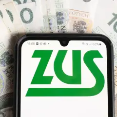 ZUS na ekranie telefonu, w tle polskie banknoty. Informacje o stopie procentowej składek na ubezpieczenie wypadkowe.