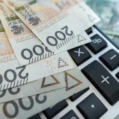 Polskie banknoty 200 zł leżą na kalkulatorze. Obliczanie pcc.