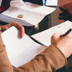 Ręce zapisują rachunki, szukając informacji o gwarancji bankowej.