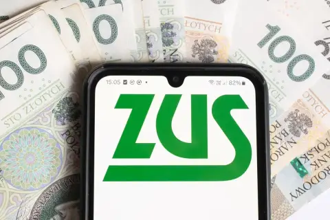 Telefon z logo ZUS na tle banknotów 100 zł. To symbol współpracy i finansów.