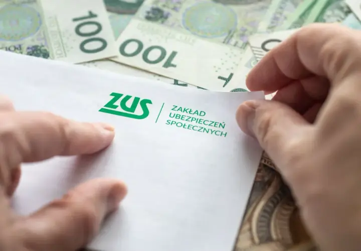 Dłonie trzymają dokument ZUS na tle banknotów 100 zł. Może to być związane z jednorazową wypłatą z subkonta ZUS.