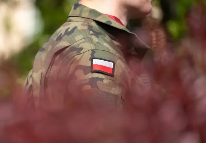 Żołnierz w mundurze moro z polską flagą na ramieniu, symbolizujący zasłużoną emeryturę wojskową.