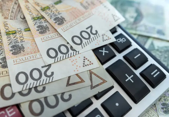 Polskie banknoty 200 zł leżą na kalkulatorze. Obliczanie pcc.