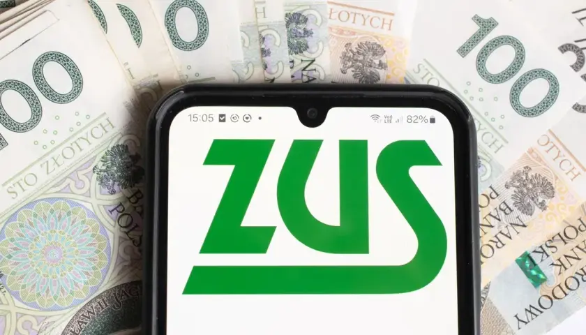 Telefon z logo ZUS na tle banknotów 100 zł. To symbol współpracy i finansów.