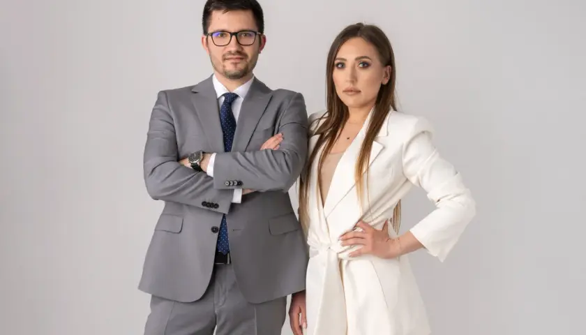 Para biznesowa w eleganckich strojach, mężczyzna w szarym garniturze, kobieta w białym żakiecie.