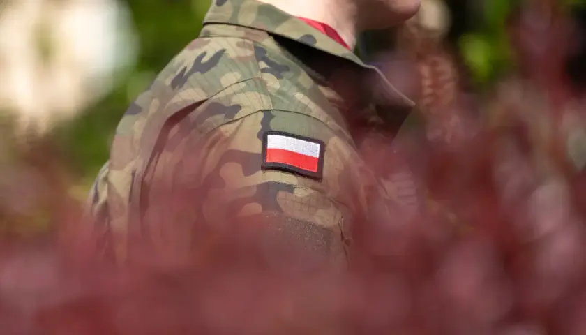 Żołnierz w mundurze moro z polską flagą na ramieniu, symbolizujący zasłużoną emeryturę wojskową.