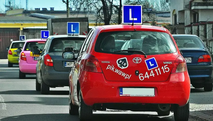 Czerwony samochód nauki jazdy z literą "L" na dachu. Zastanawiasz się, ile zarabia instruktor jazdy?