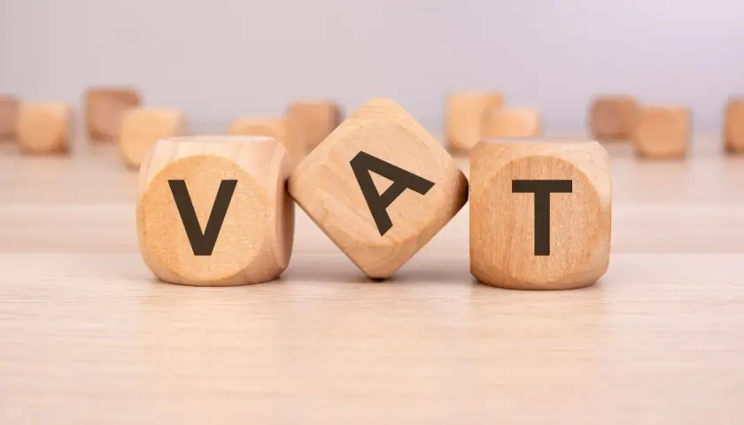 Drewniane klocki z literami V, A, T tworzą słowo VAT. To ważny element każdego formularza zaw-fa.