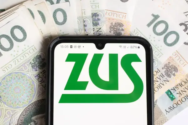 Telefon z logo ZUS na tle banknotów 100 zł. To symbol współpracy i finansów.